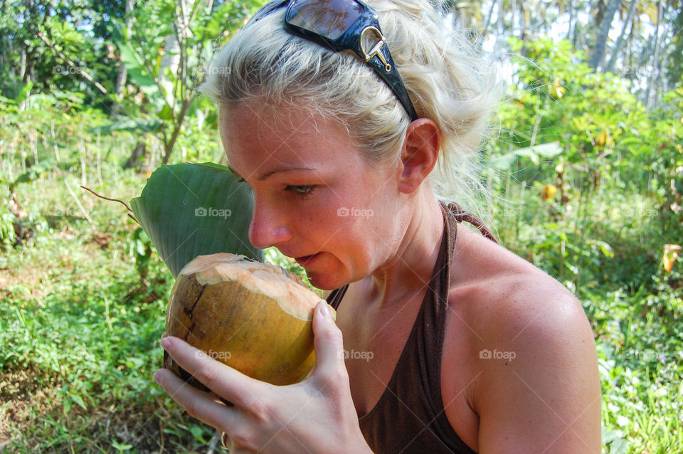 Young woman are smells a fresh coconut on Zanzibar.