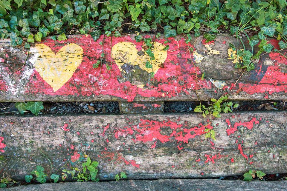 Three yellow hearts painted on a wooden bench