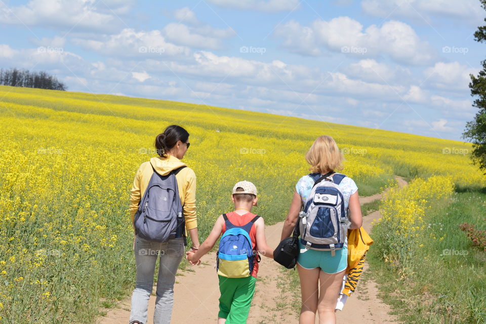 family sisters, mother and son walking in rapeseed field summer vacation