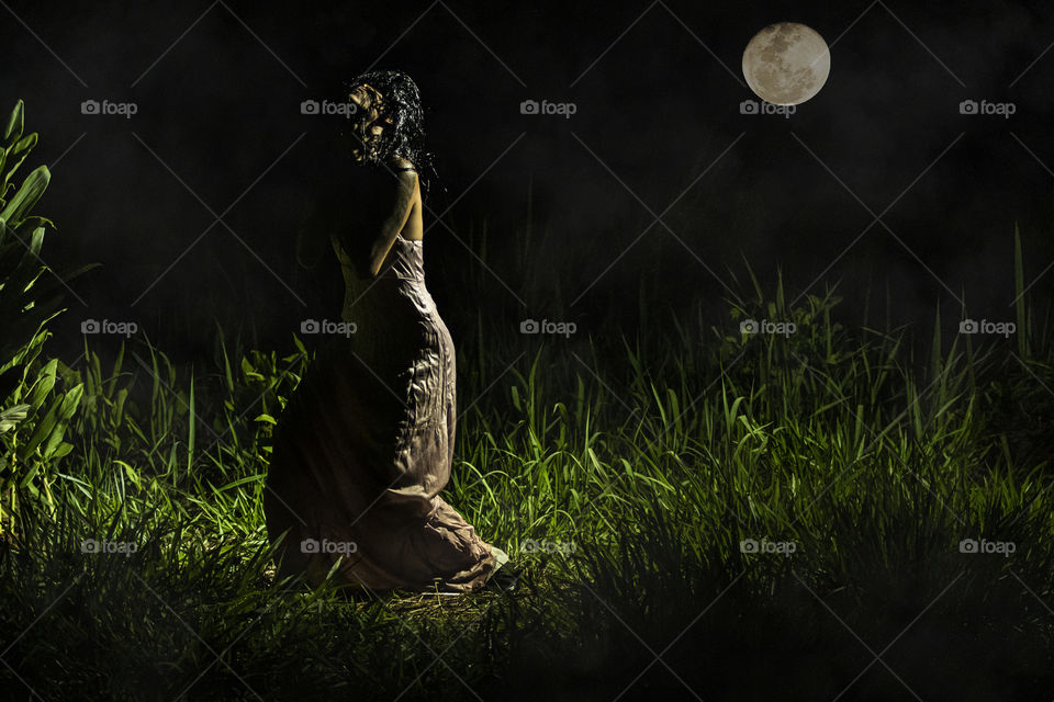 Mulher de vestido aterrorizante sobre lua cheia.