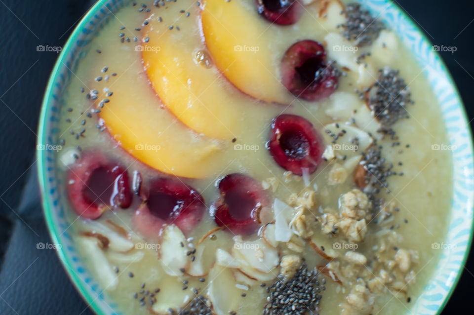 Beautiful Fruit Smoothie bowl close-up with fresh black cherry, peach sliced, oatmeal, chia seed and almonds part of a series artisanal food photography 