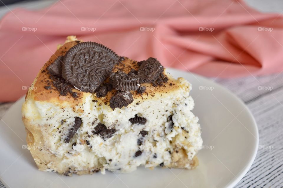 Oreo cookie cheesecake on a white plate with a pink napkin in the background