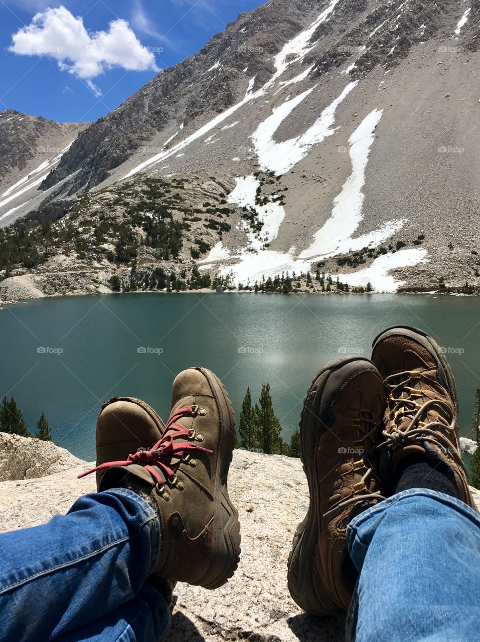 A couple kicks up their feet to relax after a challenging hike to an alpine lake.