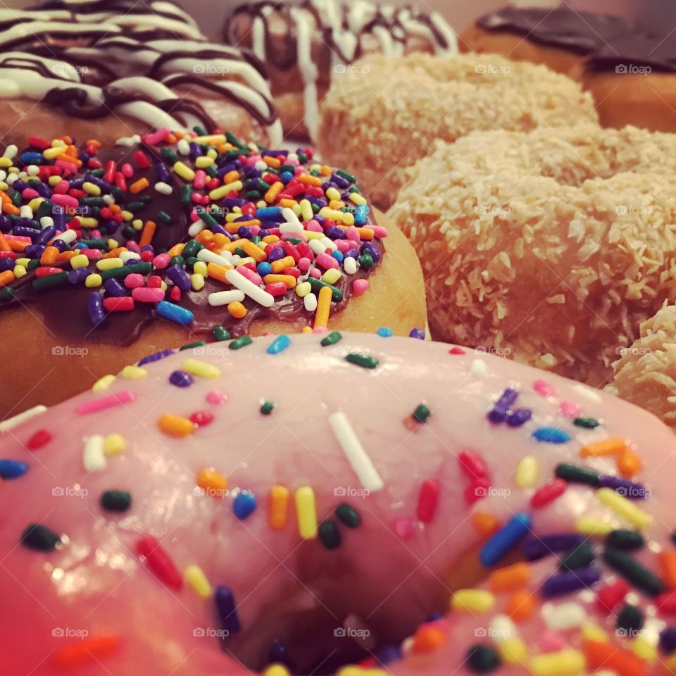 Box of assorted donuts, some with sprinkles, some with coconut, and some with cream and chocolate 