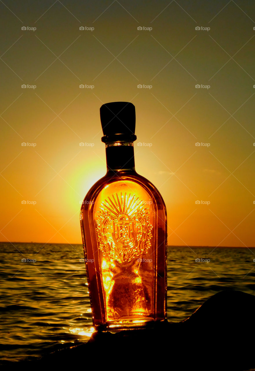 A bottle of wine on water in sea during sunset