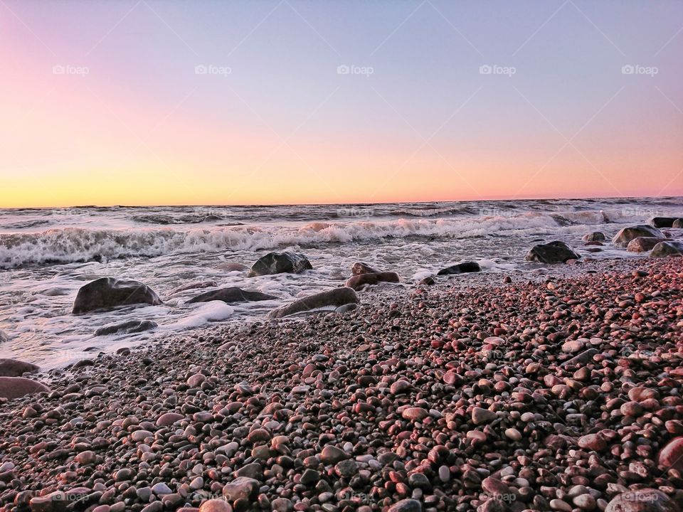 Simple sunset shot on the wavy and rocky seashore.