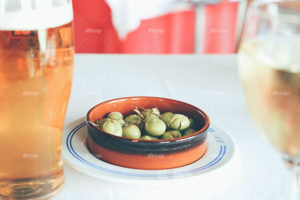 Green olives and cold drinks on a white table