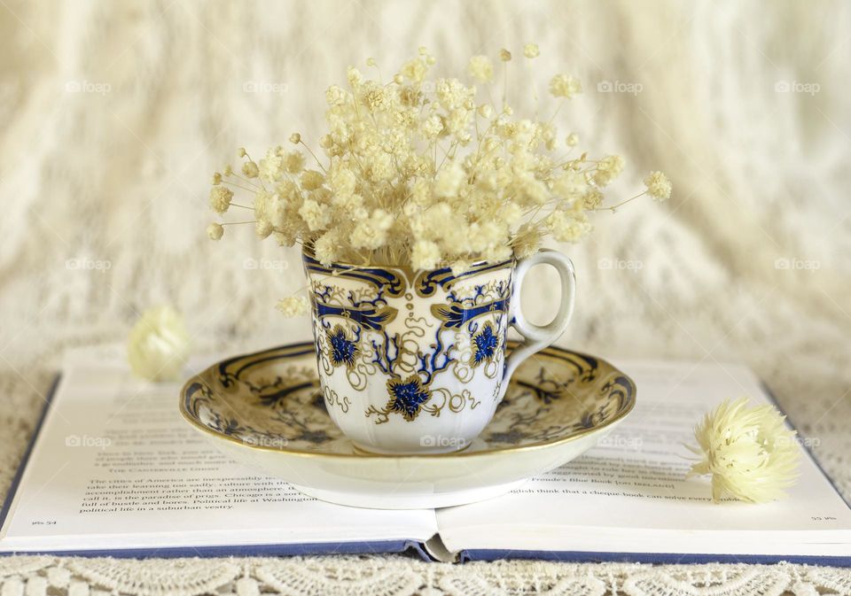 Victorian teacup with dried flowers on an open book