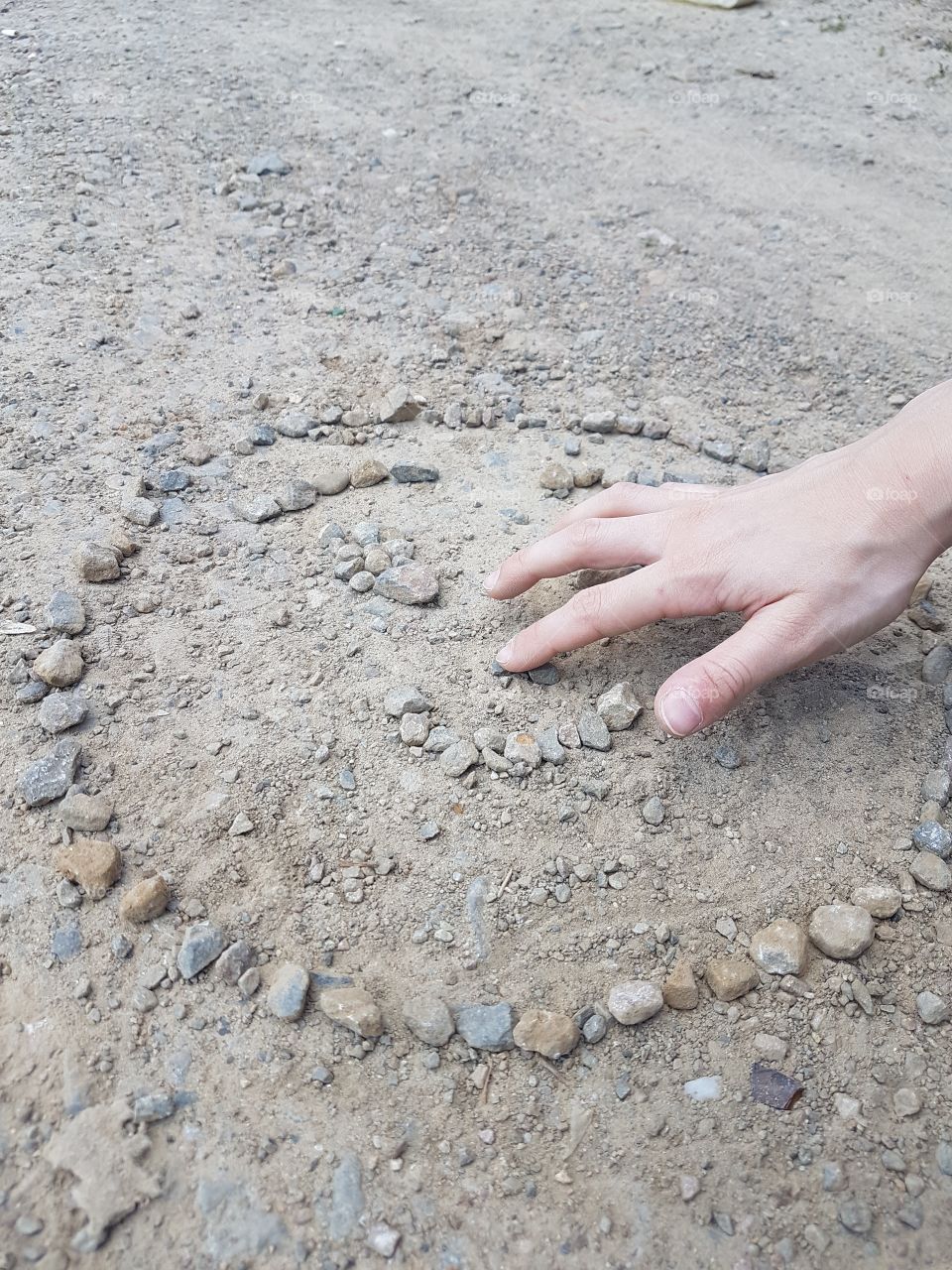 kids hand on the ground with rocks