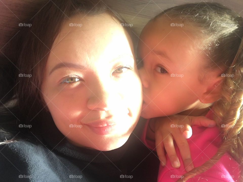 Cute little girl kissing her mother