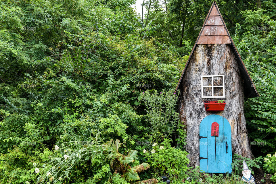Landscape image of a wooded area and a tree trunk constructed into a decorative mini house