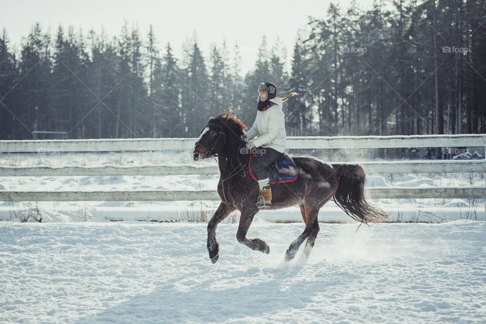 Teenage girl horseback jumping at cold winter day 