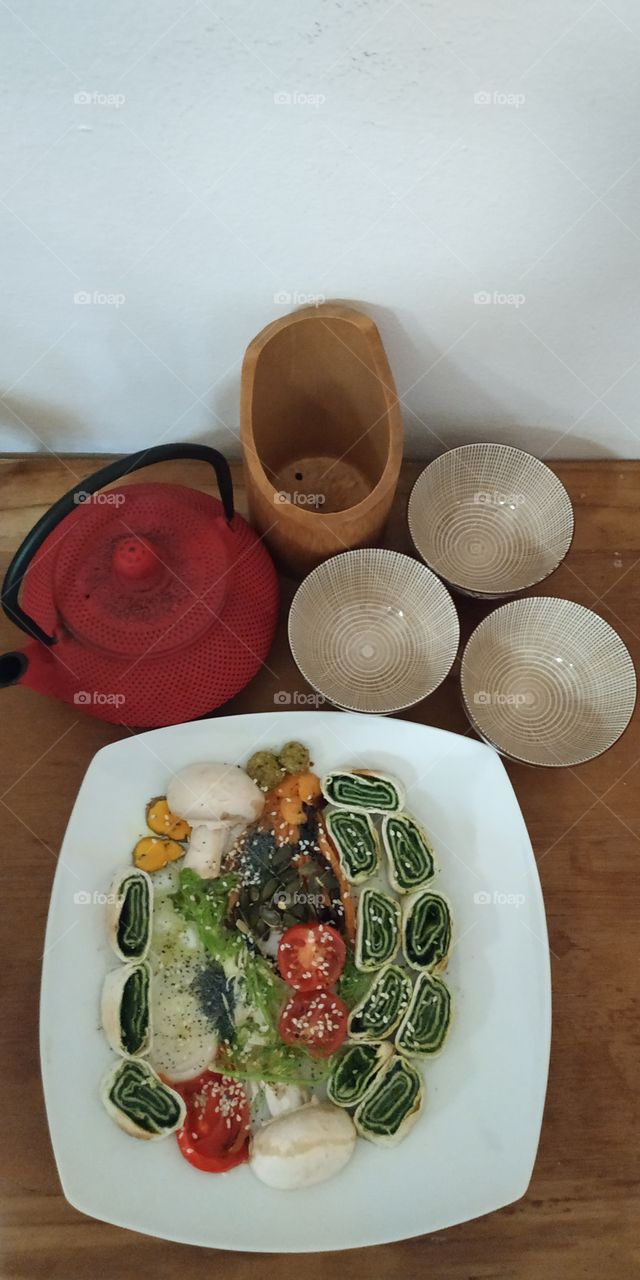 Vegetarian food on my table, in the kitchen. It is a cream of garlic, parmesan and spinach, rolled in a sheet of flour and water the other elements are vegetables and seeds. Enjoy your meal