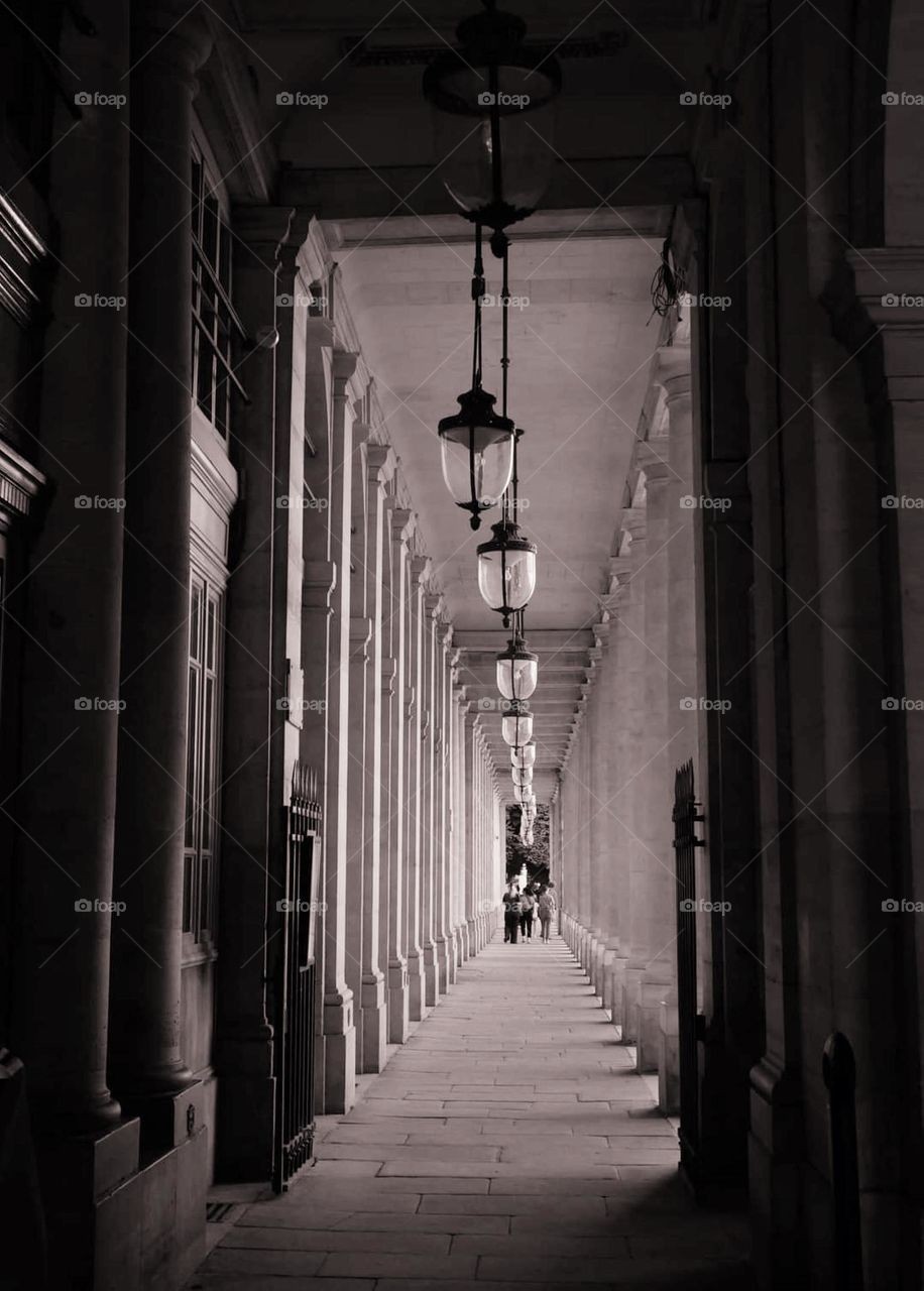 Sepia shot of the suspended lanterns of the column-lined alley called "les colonnades" of the Royal Palace in Paris