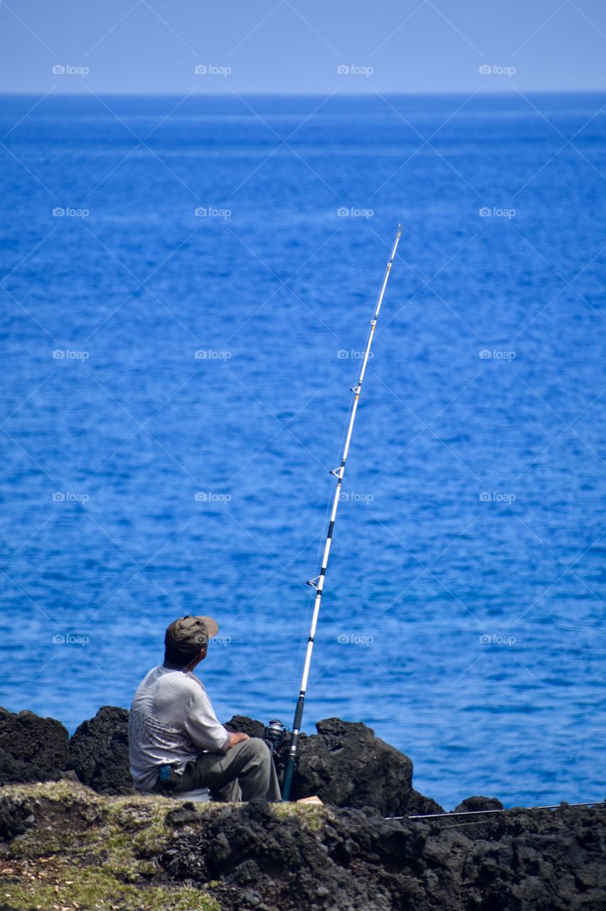 Fisherman on the sea cliffs of lava rock on the east side of the Big Island of Hawaii