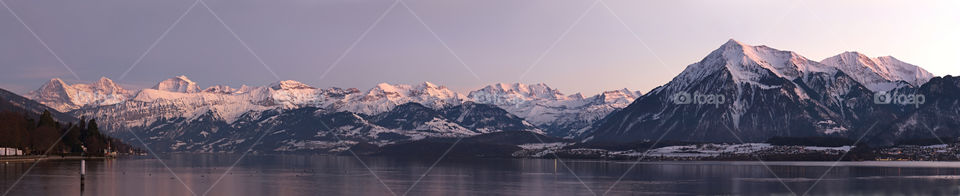 Panorama of snowy mountains behind lake
