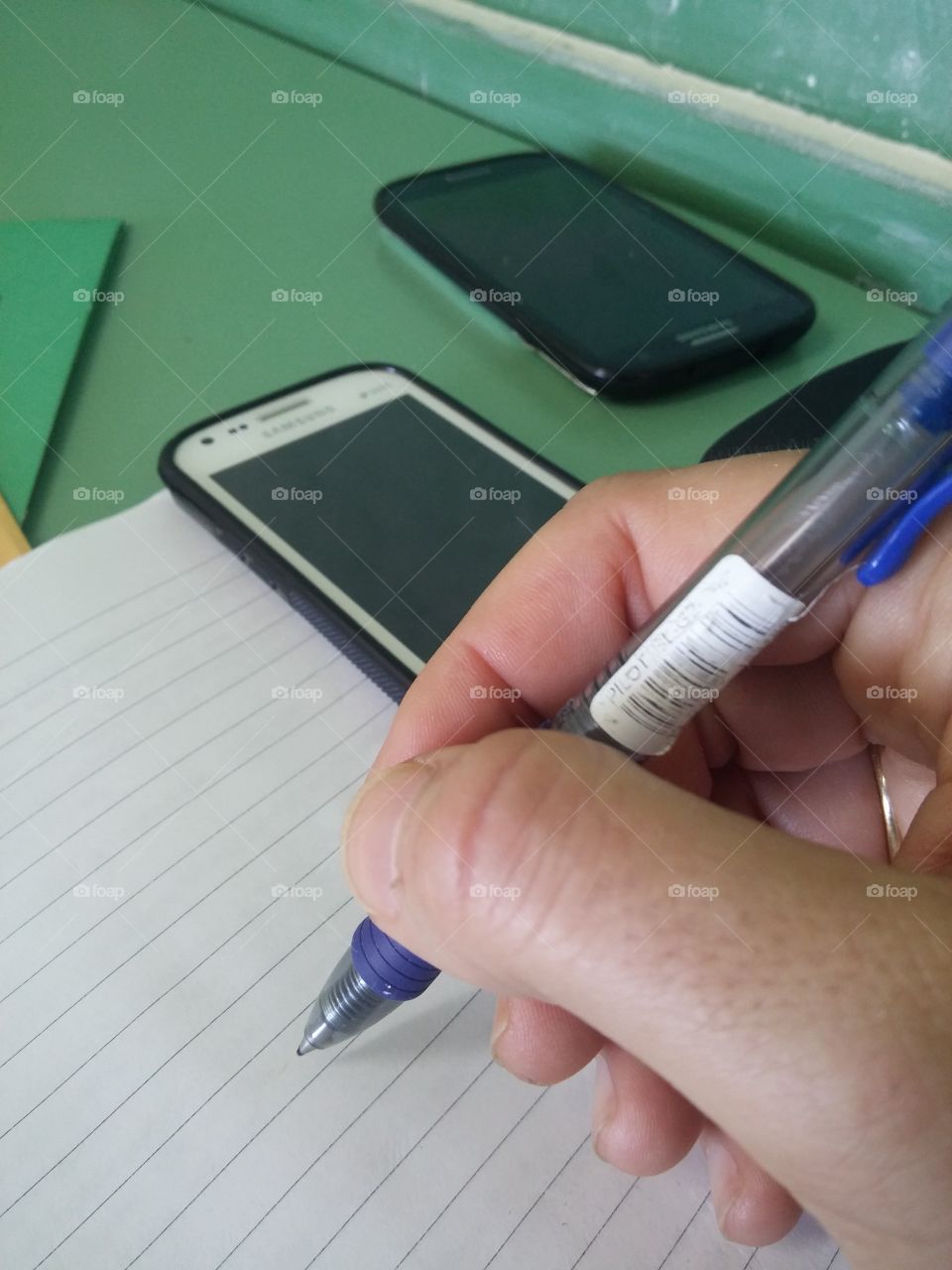 Hand holding pen for write on notebook with mobile