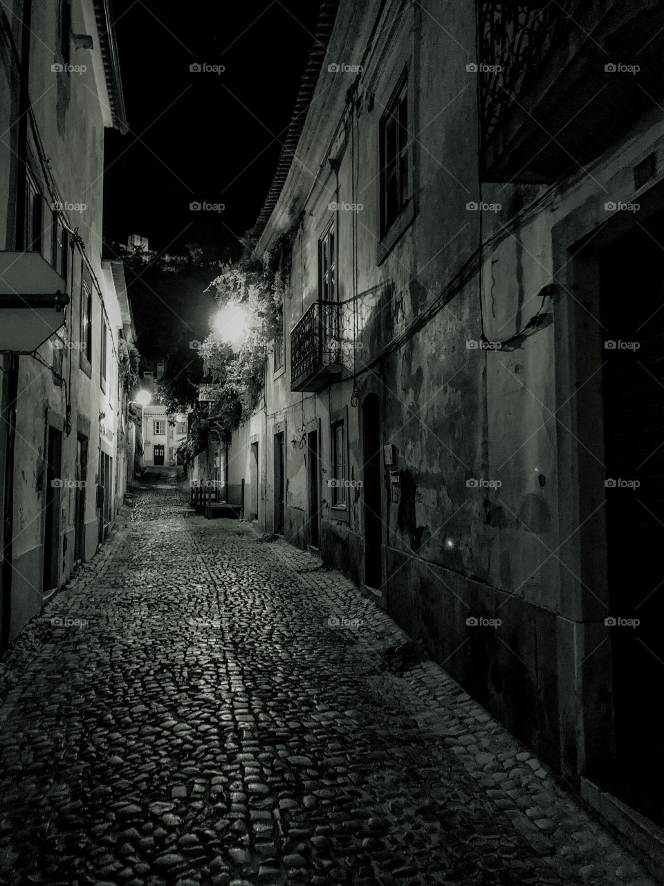 A black and white image of a cobbled street dimly lit by one street lamp, Tomar, Portugal 