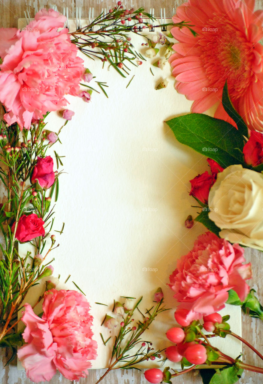 Spring, flowers, floral border, flower border, flat lay, white paper, wooden background, pink flowers and leaves, carnations, portrait orientation