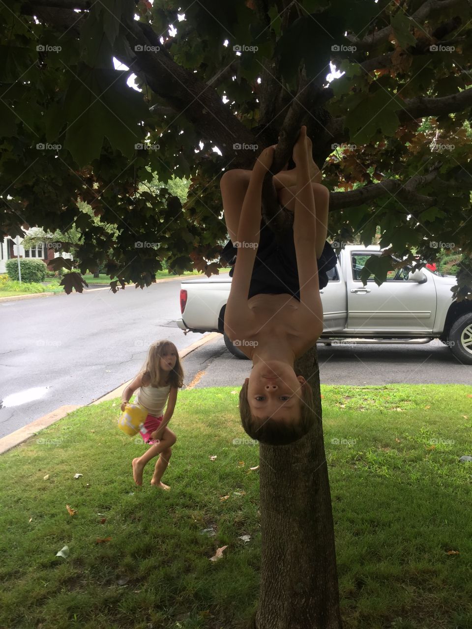 Little boy hanging on tree upside down