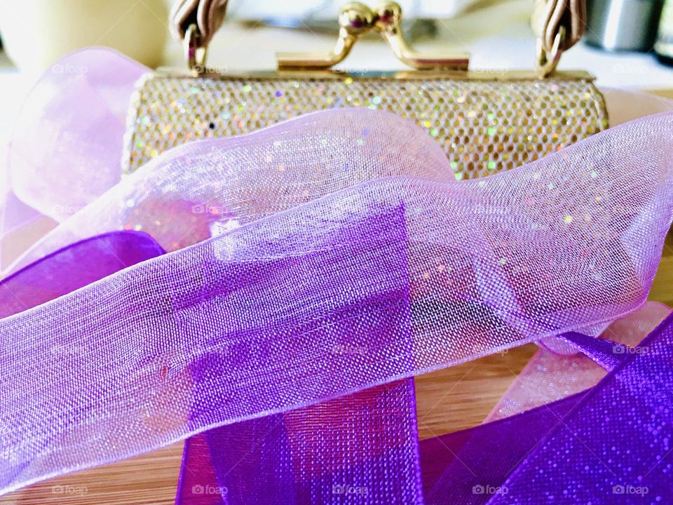 Lavender strips of translucent sheer and sparkling organza ribbon, soft, feminine and fashionable, wide in various hues set against backdrop of sparkling formal evening clutch purse , concept fashion design, various hues 