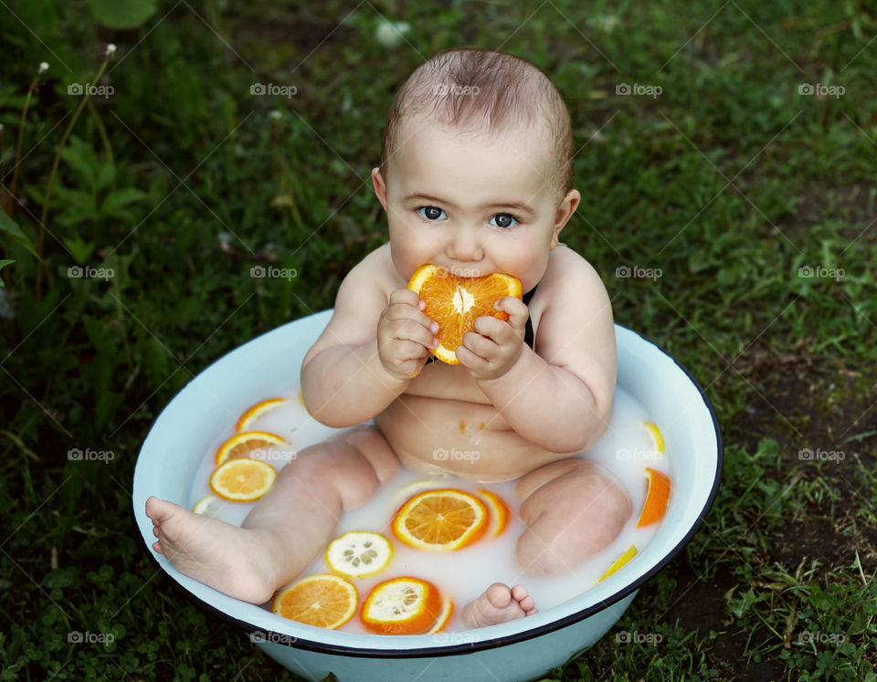 the boy sits in the pelvis and eats oranges