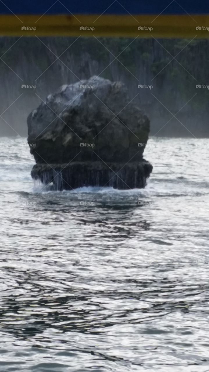 Lone rock battered by waves in the ocean