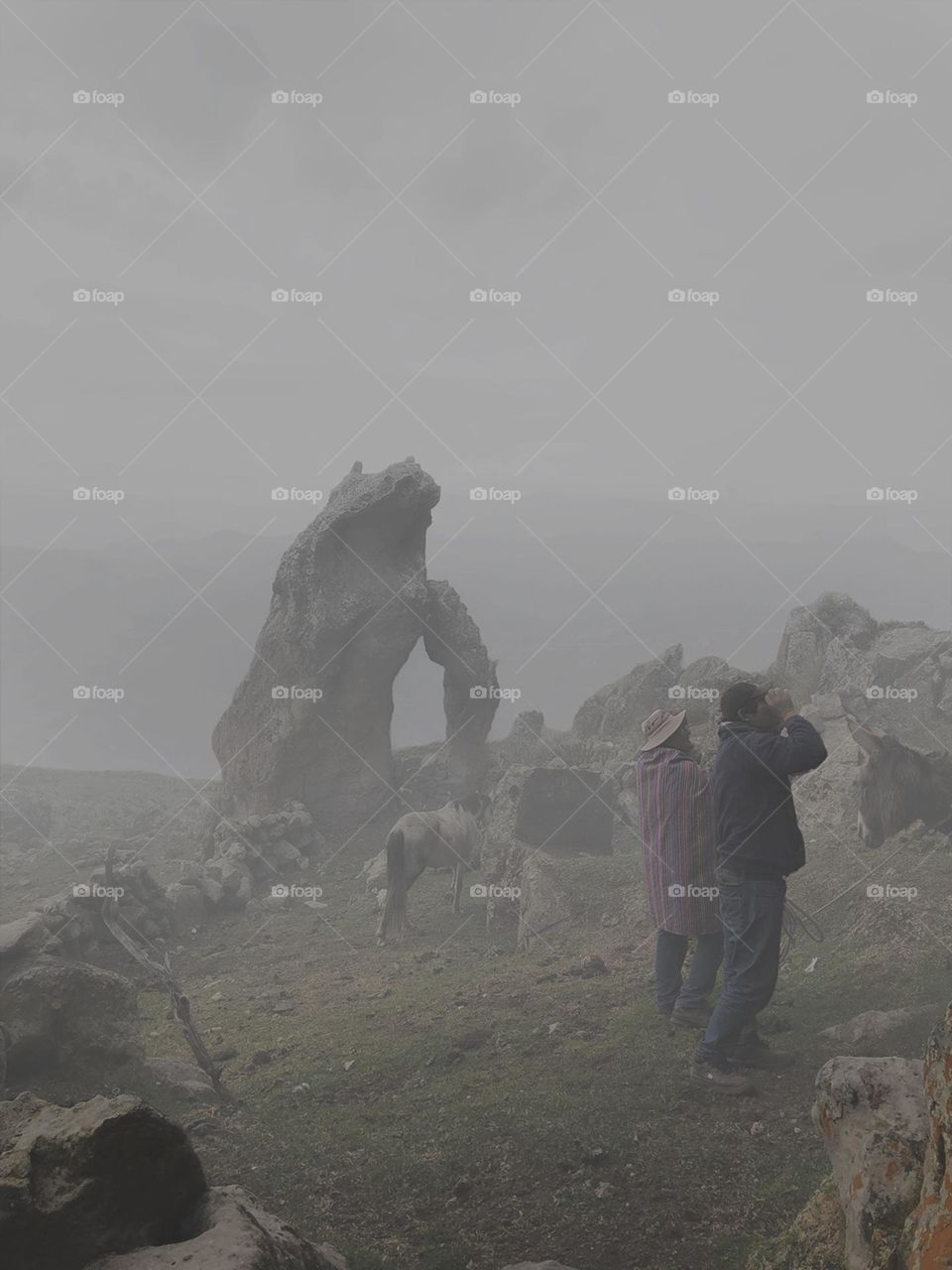 People in foggy sunset on rocky mountain 