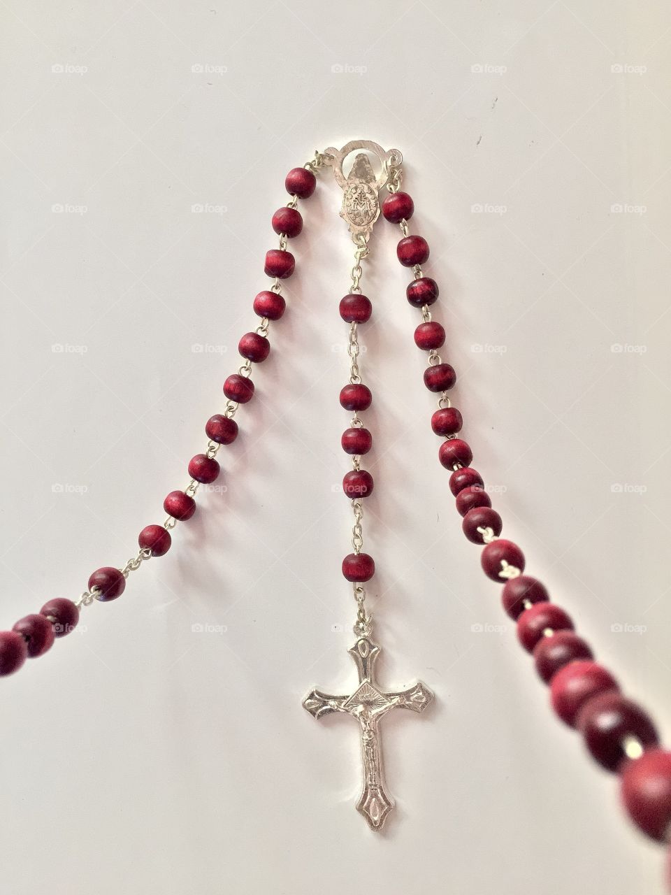 Red bead rosary against a white background 
