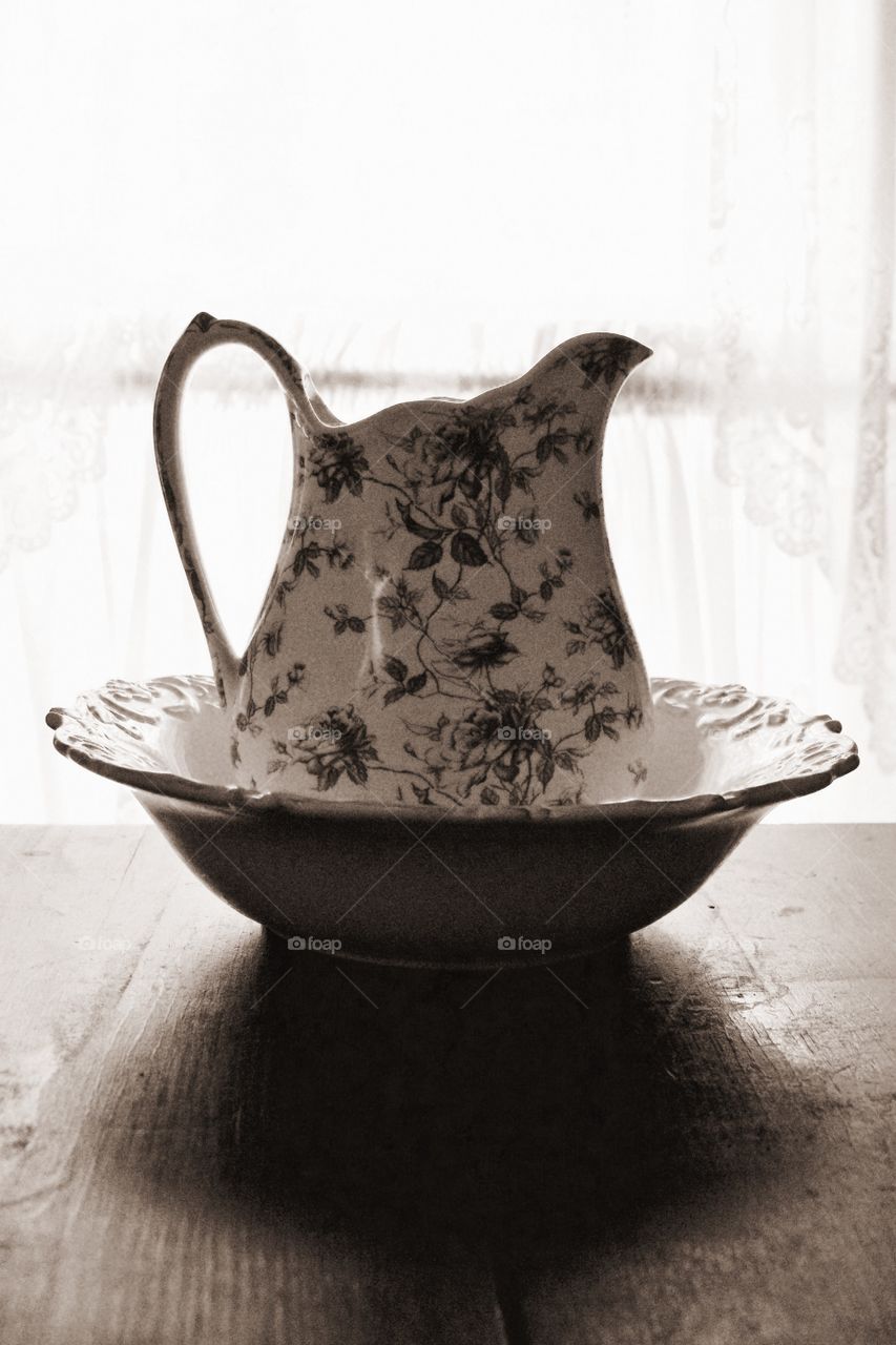 Minimalistic Snaps - backlit pitcher and basin on a wooden surface 