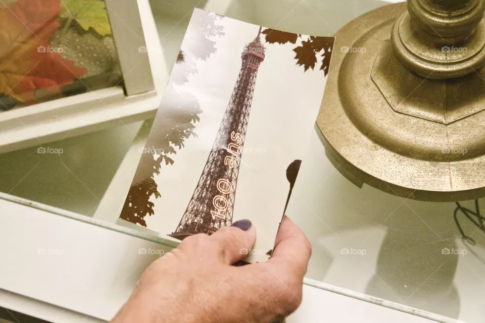 A woman looking at her old photo of when she went to Paris, France in 1989 when Paris hosted an Exposition Universelle (World’s Fair) to mark the 100 year anniversary of the French Revolution. The Eiffel Tower had a special 100 Ans light on the side!