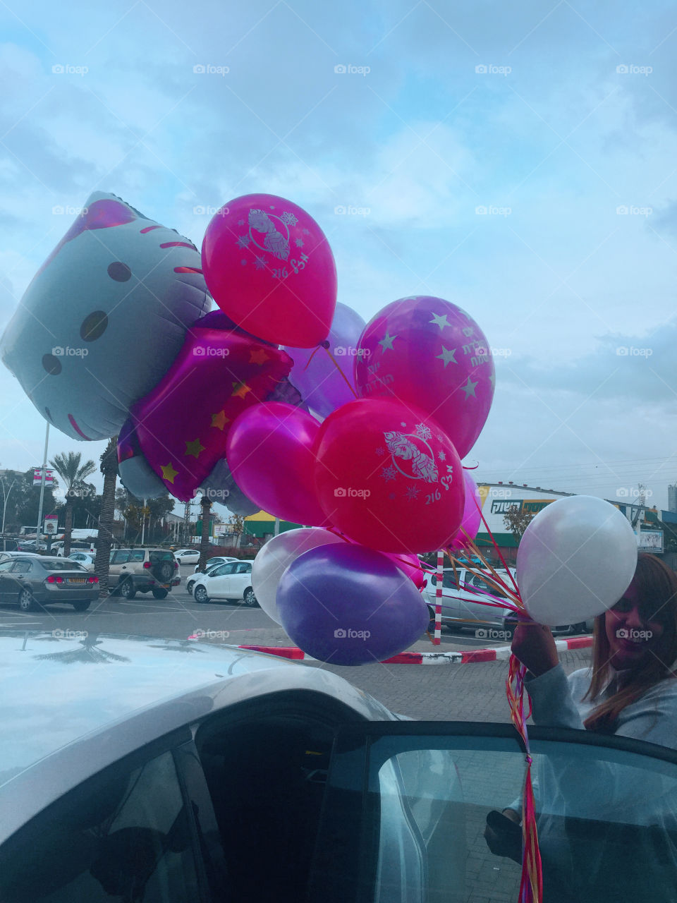 Woman holding bunch of balloons