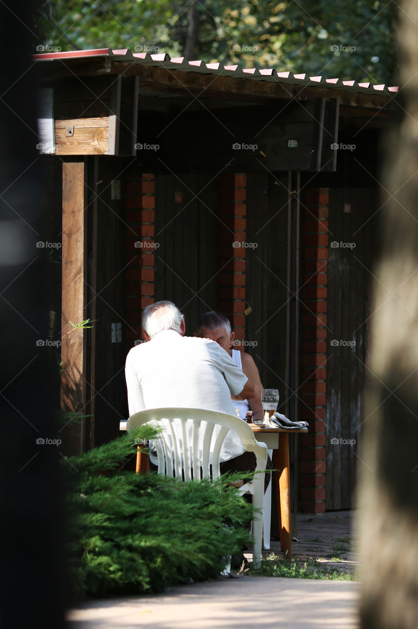 Two elder friends playing chess in the shade