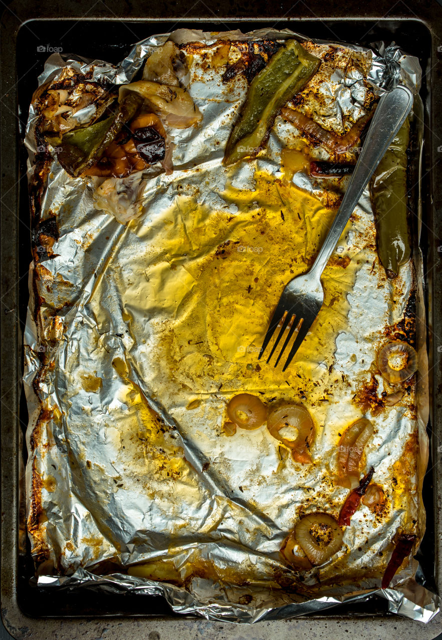 baking tin on it foil, fat, dirty fork and leftovers after roasting