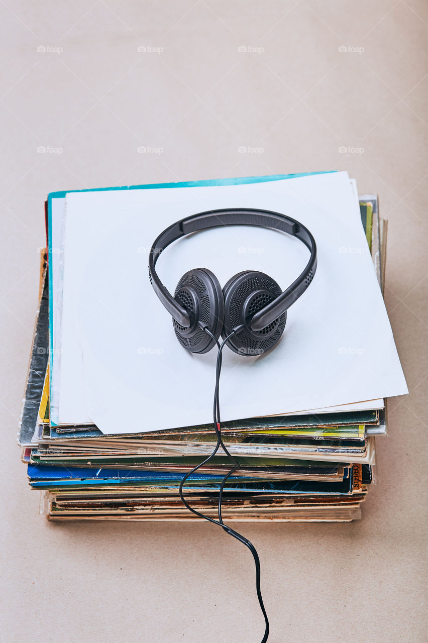 Stack of many black vinyl records and headphones on the top of stack. Candid people, real moments, authentic situations