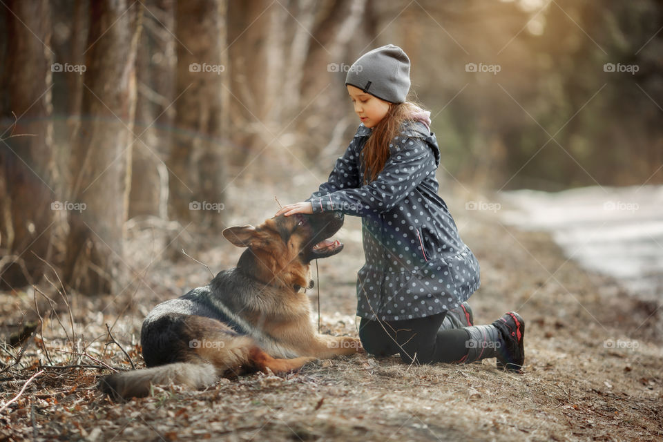 Girl walking with German shepherd puppy in a spring forest 