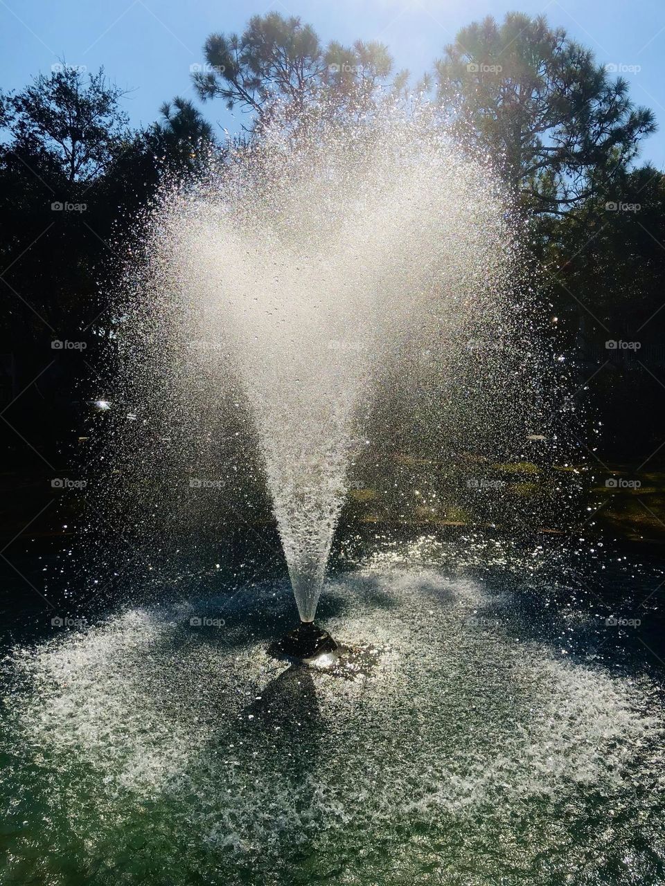 Sunlight through the spray of a fountain in a city park. Everyday beauty outdoors.
