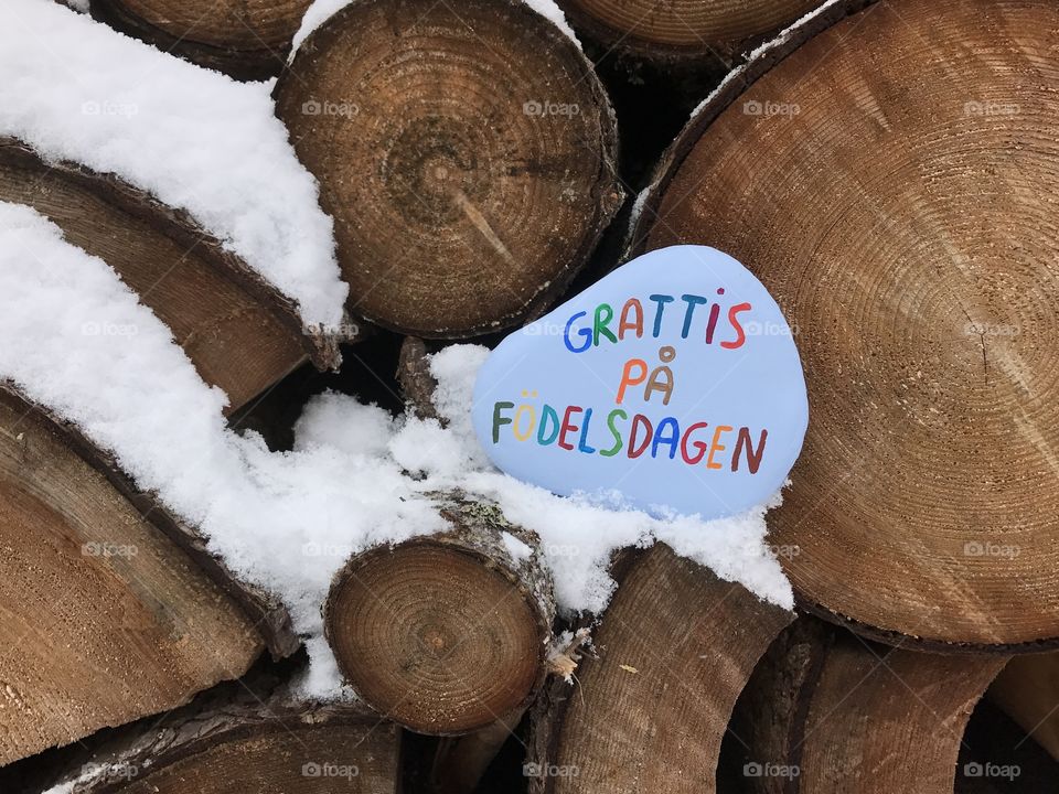 Grattis på födelsedagen, swedish Happy Birthday on a stone with cutted trunks background