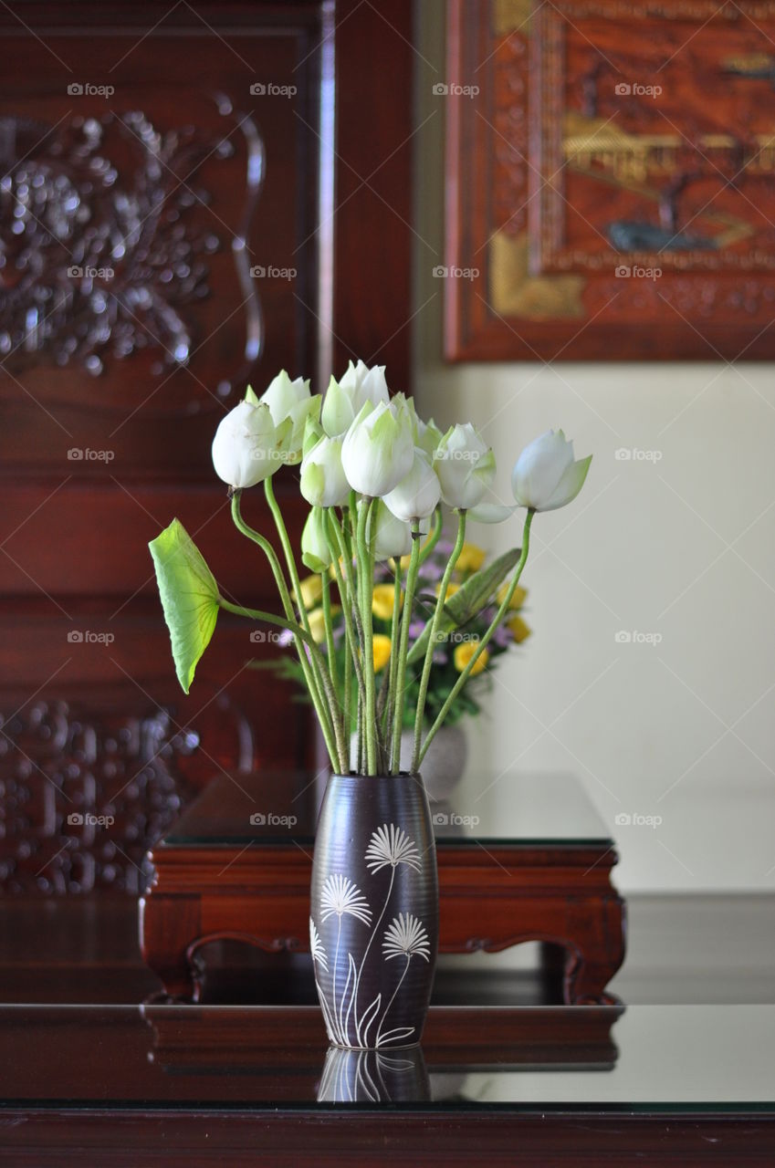 White lotus and green leaves in earthenware flowerpot/jar/vase in room. Bình hoa sen trên bàn