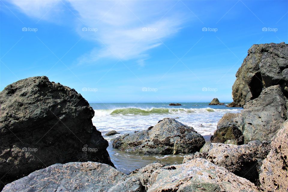 The Brookings, OR along the beach with tall rocks and a wave coming in 