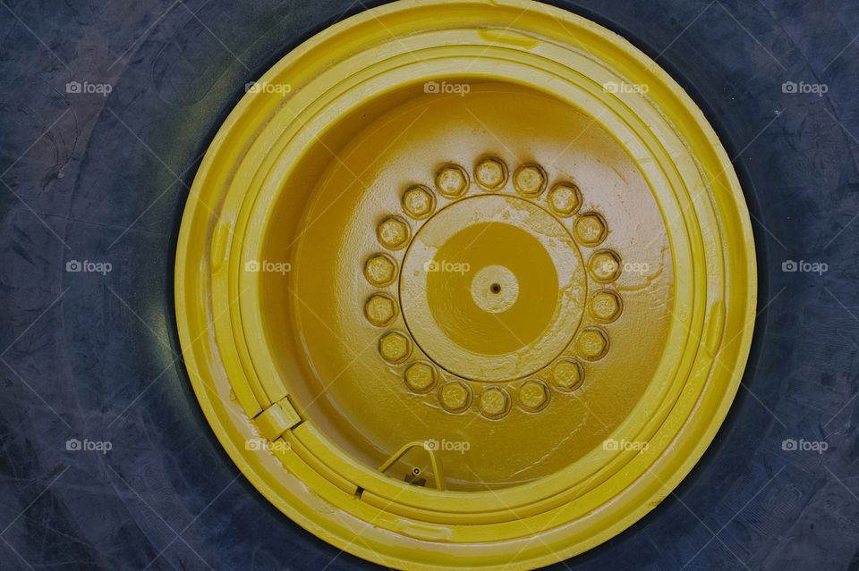 An closeup of a large tractor tire and gold colored rim.