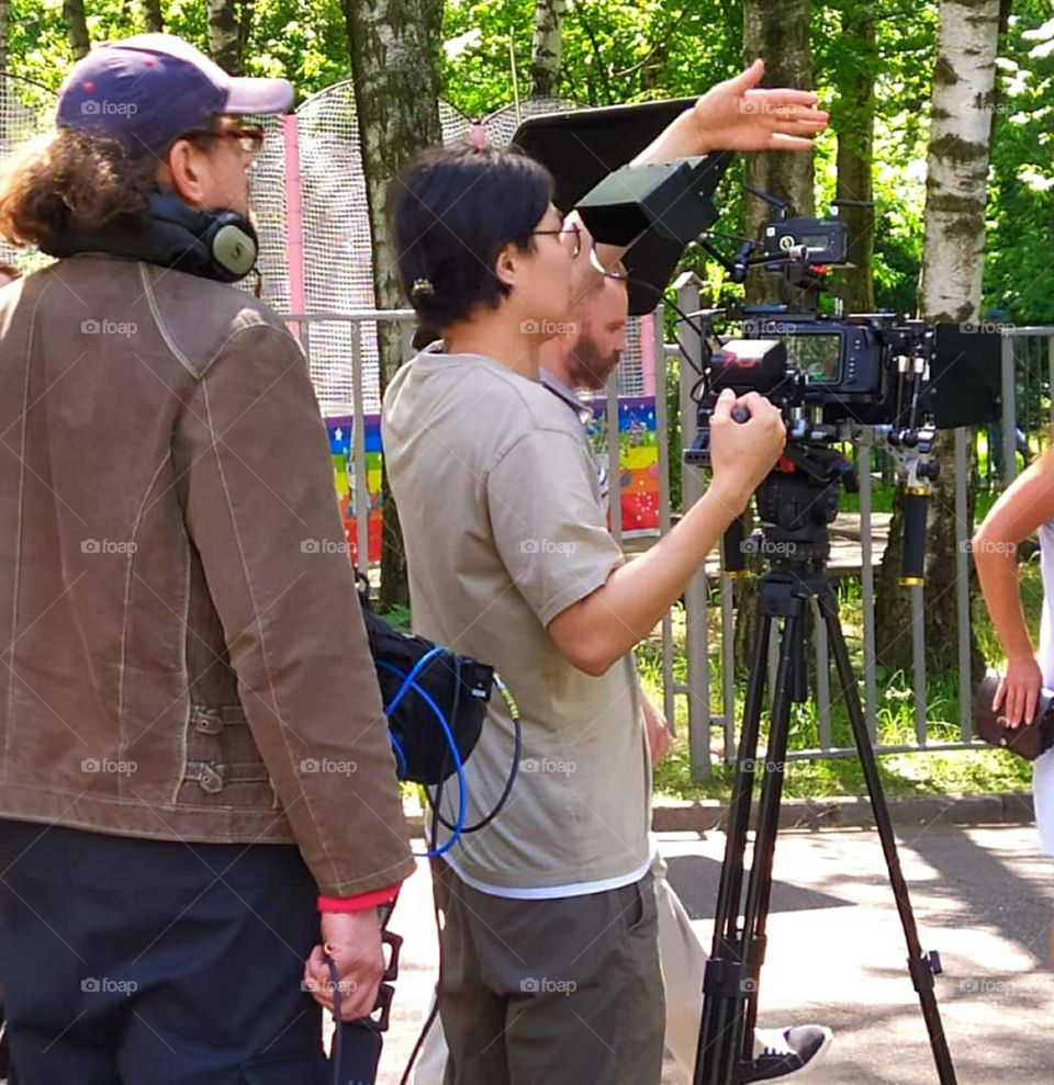 Summer in the city.  In the park, among the green trees, a movie is being shot.  In the main plan is a cameraman waving to the actors.