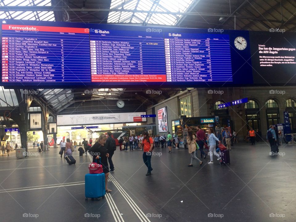 Zurich Hauptbahnhof or main train station which is busy with commuters and the train departure board 