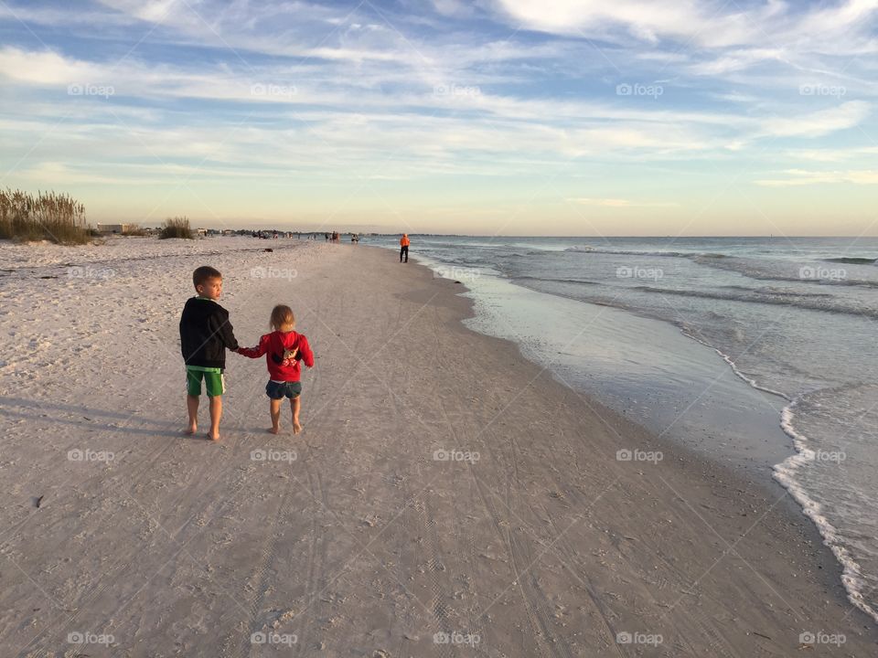 Siblings enjoying a midday walk on the beach 