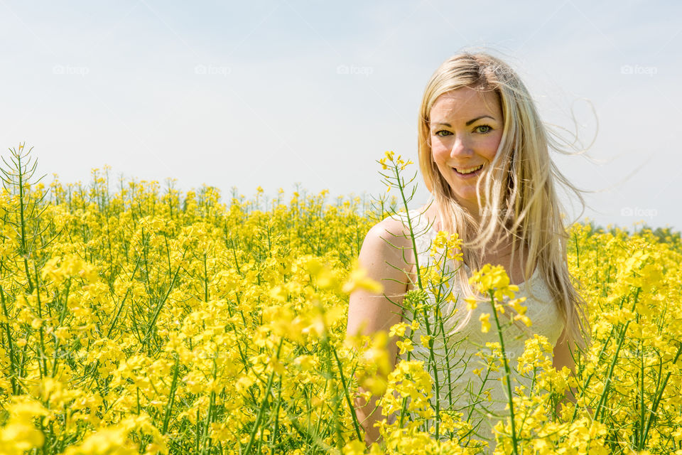 Close-up of a happy woman in yellow oil rape seed field