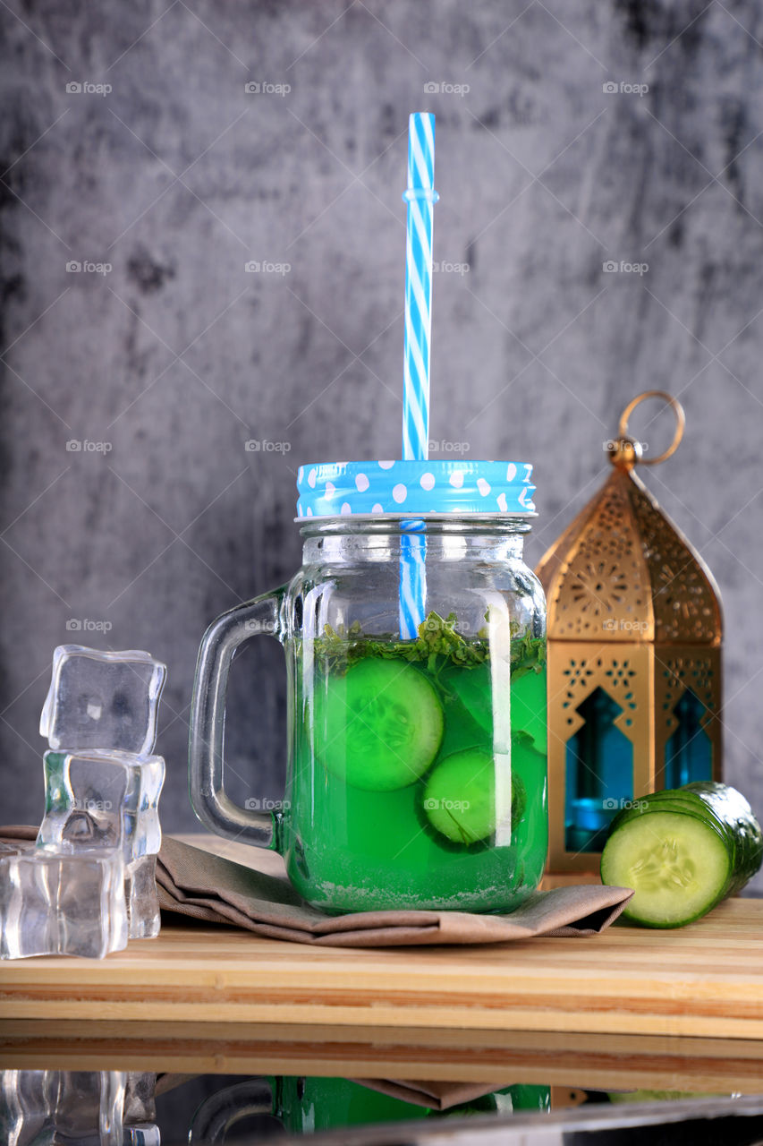 Mason jar with cucumber juice, ice cubes and lantern