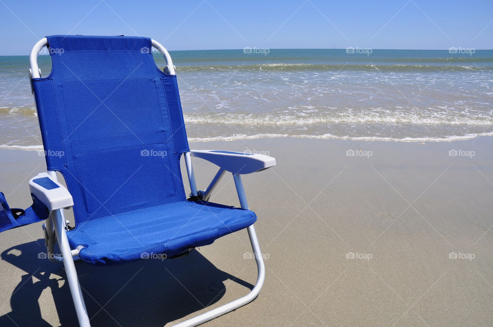 Blue beach chair on the sand room for your copy.