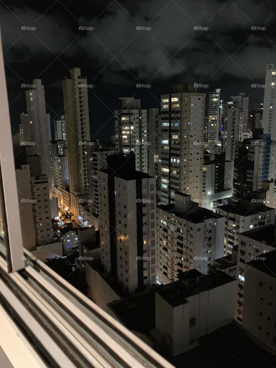 Edifícios vistos à noite de uma sacada. Muitas janelas com luzes.