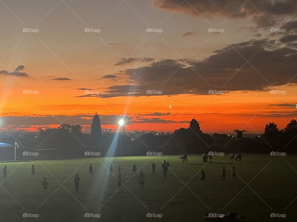 Magnificent sunset over field of children playing 