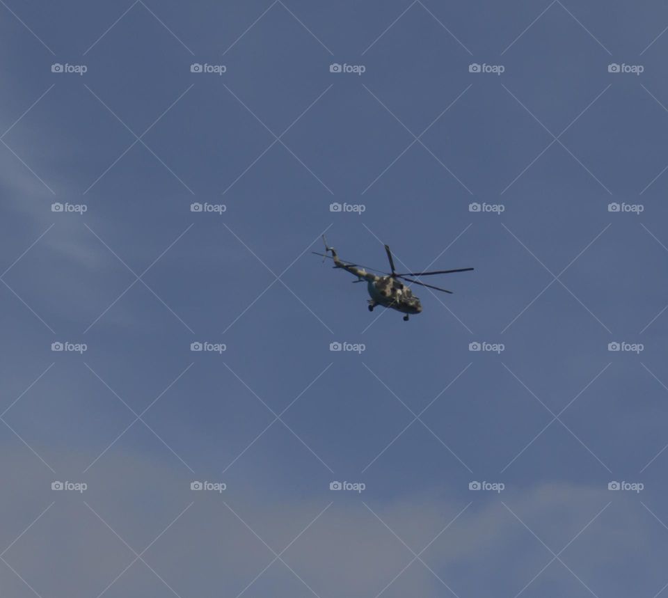 The helicopter is flying against the blue sky.